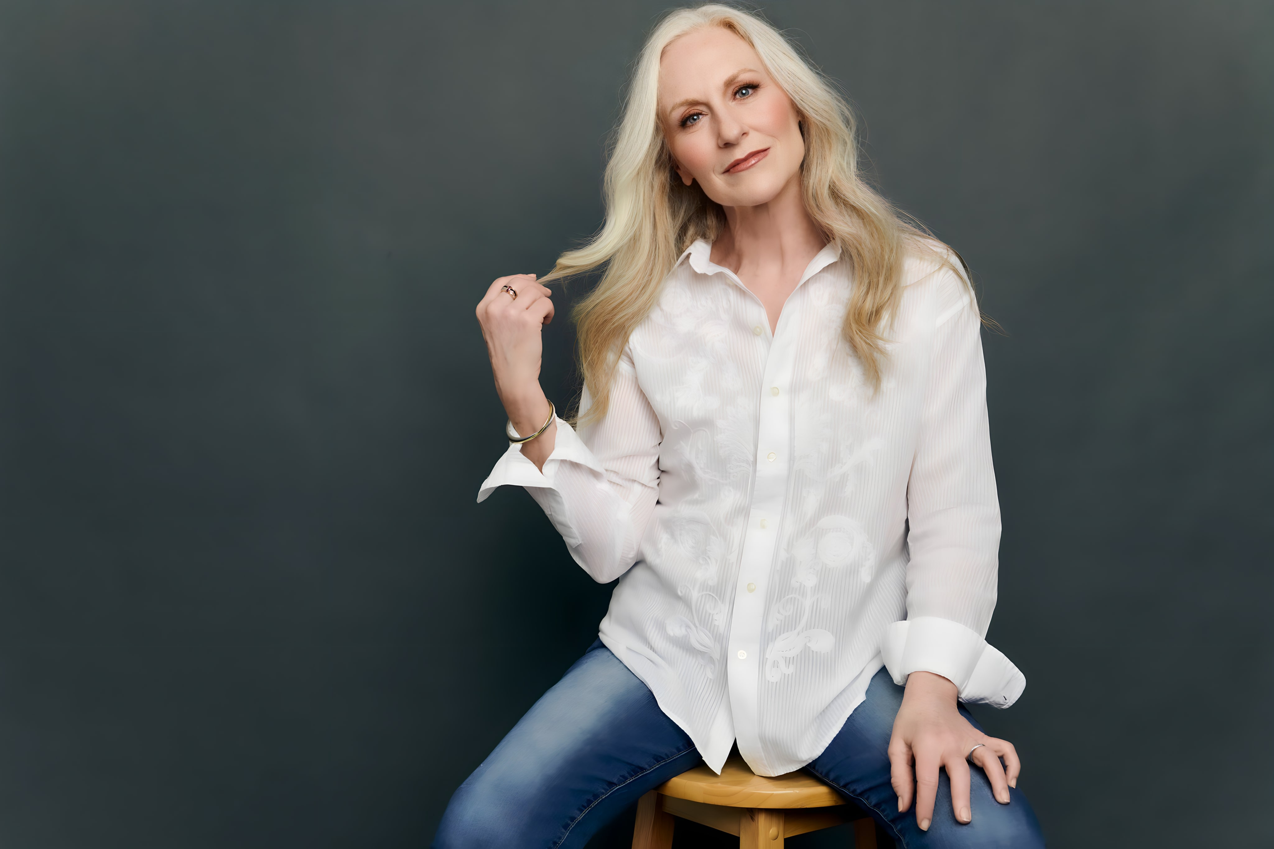 Woman in white shirt and jeans sitting on wooden stool