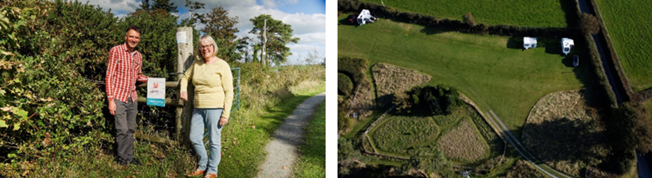 Two people standing beside a sign in a rural area, with greenery and trees in the background.